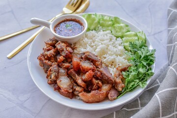 Fried pork with rice and vegetables on a white plate, thai food