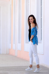 Young woman posing in blue shirt and white jeans