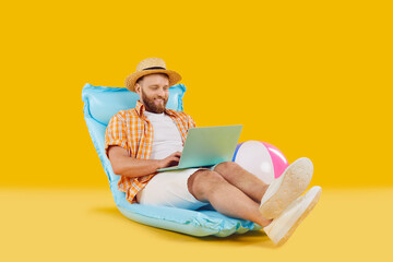 Funny man in casual summer clothes relaxing sitting on inflatable mattress working or booking...