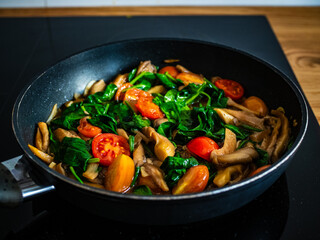 Oyster mushrooms with spinach and tomatoes in frying pan