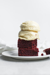 Fudgy red velvet brownies with cream cheese ice cream on a white plate, red velvet fudge brownies on a white background