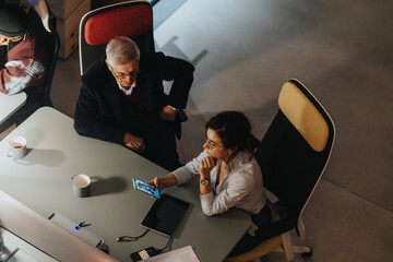 Bird's-eye shot of an attentive female professional holding a smart phone during a serious business meeting with a male colleague. © qunica.com