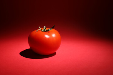  Red tomato with a green stalk, on a red background