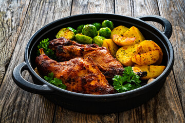 Cooked rabbit thighs with potatoes and brussels sprout in frying pan
