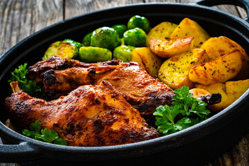 Cooked rabbit thighs with potatoes and brussels sprout in frying pan
