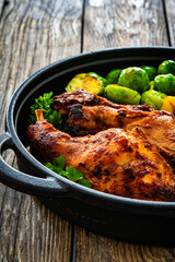 Cooked rabbit thighs with potatoes and brussels sprout in frying pan
