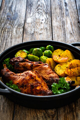 Cooked rabbit thighs with potatoes and brussels sprout in frying pan

