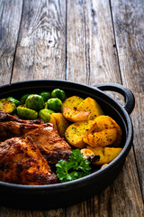 Cooked rabbit thighs with potatoes and brussels sprout in frying pan
