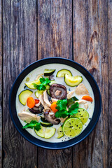 Tom Kha Gai soup - Thai soup with chicken breast nuggets and noodles on wooden table