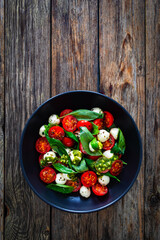 Caprese salad with pesto sauce on wooden board

