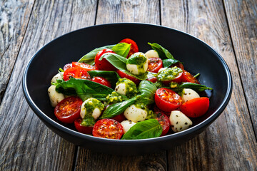 Caprese salad with pesto sauce on wooden board
