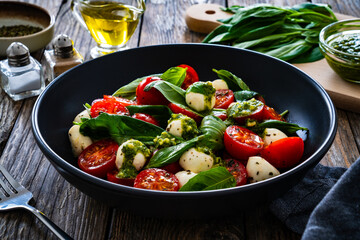 Caprese salad with pesto sauce on wooden board
