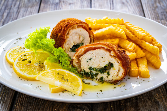 Cutlet de Volaille served with French fries and lemon on wooden table
