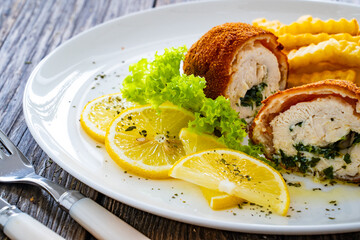 Cutlet de Volaille served with French fries and lemon on wooden table
