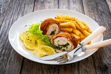 Cutlet de Volaille served with French fries and lemon on wooden table
