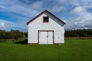 White clapboard shed with red roof and trim at the Lobster Cove Head Lighthouse at Gros Morne National Park in Newfoundland, Canada. 
