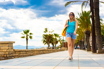 Beautiful woman walking on seaside boulevard - Costa Dorada Spain
