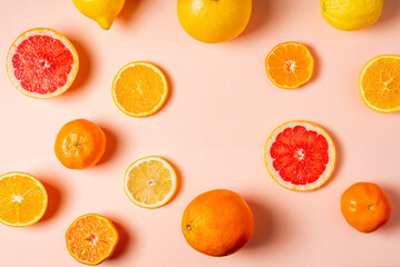 Collage of citrus fruits, whole, half and sliced, grapefruits, oranges, lemons and tangerines on a pink background, top view.