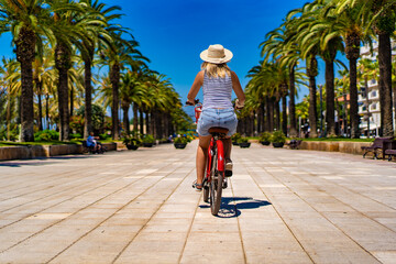 Woman riding bicycle on seaside boulevard Costa Dorada Spain
