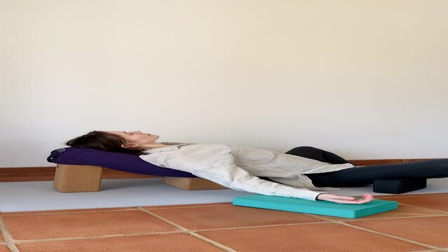 Woman doing restorative yoga supported butterfly pose with props
