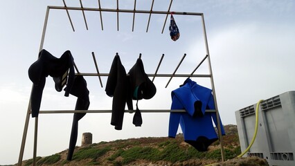 Diving suits and a swimsuit hanging out to dry in the sun after an intense day in the water.