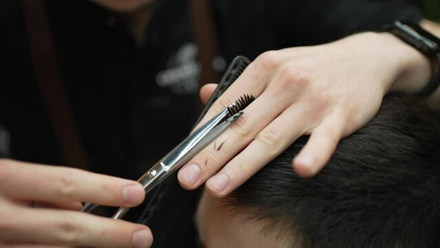 Hairdresser makes man's hairstyle with scissors