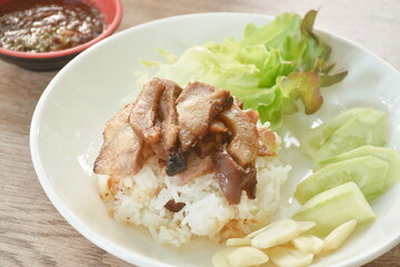 slice grilled pork neck topping rice with cucumber and garlic dipping spicy chili tamarind sauce on plate