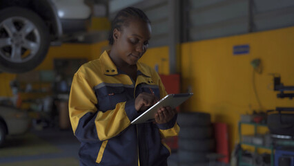 A woman wearing a yellow and blue jacket is looking at a tablet. She is smiling and she is enjoying her work