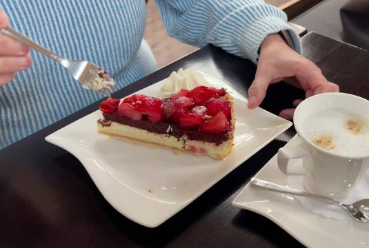 Frau isst Erdbeerkuchen mit einer Gabel