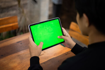 Mock up photo of a close up shot featuring a mans hand holding an iPad tablet with a green screen...