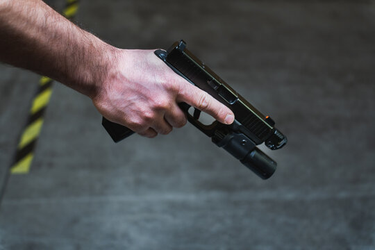 Tactical pistol with a flashlight in a man's hand, close-up photo.