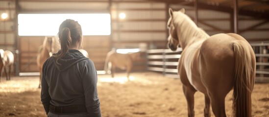 Female instructor teaches horse education and training at indoor equine farm. - obrazy, fototapety, plakaty