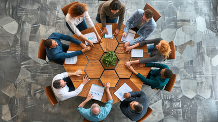 top-down view of a diverse group of professionals engaged in a meeting around a hexagonal wooden table with documents and a central potted plant