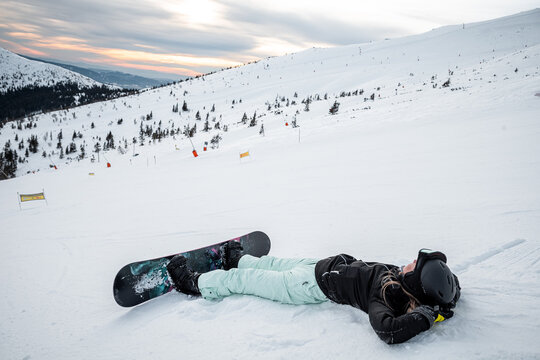 Woman laying down on a ski slope watching a beautiful sky