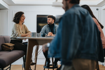 Group of young adults in casual wear involved in a light-hearted business meeting at a modern office space, evoking a sense of collaboration and team spirit.