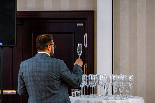 Man looking at a champagne glass to make sure it is clean