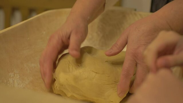 Grandmother and Niece Kneading Bread  In A Traditional Wooden Trough.
