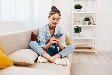 Smiling woman holding mobile phone, relaxing on cozy sofa in living room