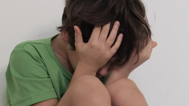 Kid crouched down, hands on face, possibly in response to a distressing situation. A strong image for social issues or child welfare content.