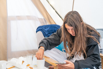 A young girl makes breakfast inside a beautiful glamping tent in a camping