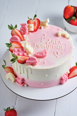 Obraz na płótnie Canvas Delicious and beautiful handmade children's cake. Delicate pink and white cake for a child. Dessert is decorated with fresh strawberries and chocolate.