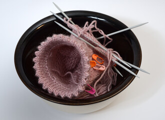 knitting from wool and knitting needles in a ceramic bowl