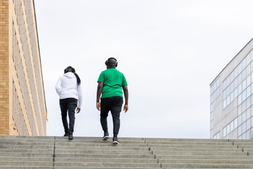 Two people climbing stairs while listening music with headphones
