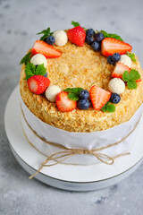Napoleon cake. Birthday cake on a stand, decorated with fresh berries and sweets.