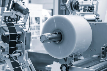 Automatic polyethylene plastic bag production machine with lighting effect. Close-up of the roller of the plastic bag production machine in the light blue scene. product packaging concept