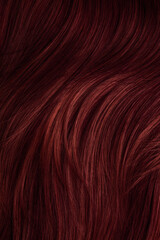 Dark red hair close-up as a background. Women's long brown hair. Beautifully styled wavy shiny...