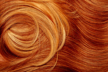 Red hair close-up as a background. Women's long orange hair. Beautifully styled wavy shiny curls....