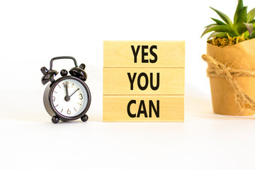 Motivational and Yes you can symbol. Concept words Yes you can on beautiful wooden blocks. Beautiful white background. Black alarm clock. Business motivational and Yes you can concept. Copy space.