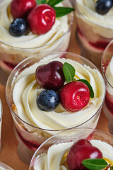 Holiday trifles with cream cheese cream and berries filling. Confectionery for the holiday. Dessert decorated with cherries and blueberries, packed in a gift box.