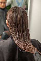 Photo of a European girl with long and beautiful brunette hair at the beauty salon. Shiny and healthy hair.